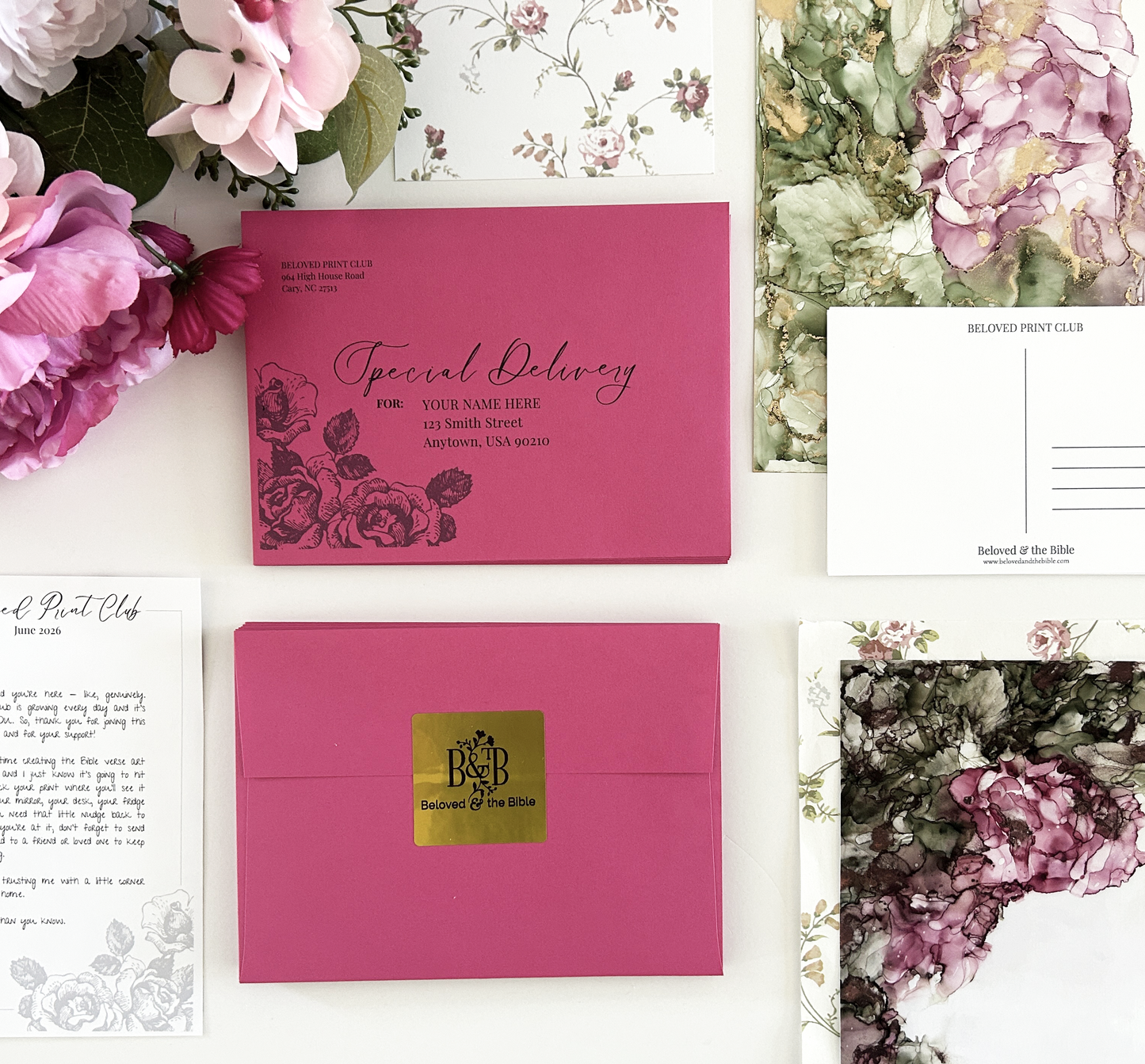 Christian Bible Verse art print snail mail club product flat lay featuring pink envelopes, alcohol ink art, a postcard, and a letter.